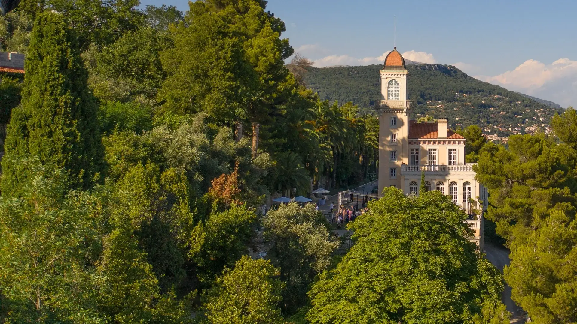 Château Saint-Georges, villa decimonónica de un perfumista con torre redonda y cúpula, emergiendo entre pinos y palmeras en una ladera sobre Grasse bajo la luz del atardecer.